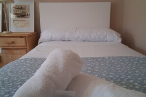 Una cama con un almohadón blanco y una manta de estrellas azules.
