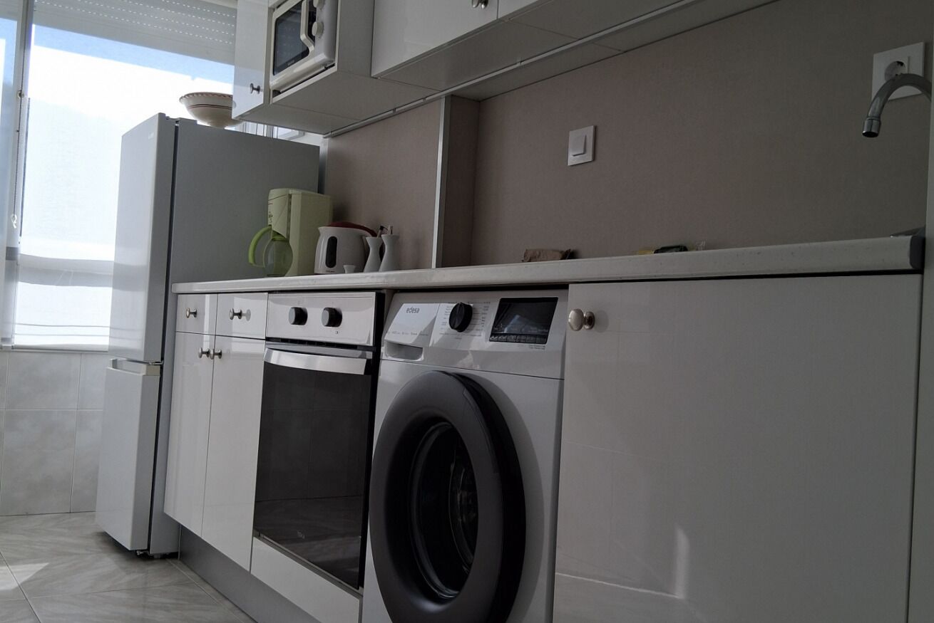 A modern kitchen with a built-in washer and dryer, a microwave, and a small oven.