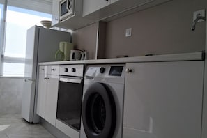 Una cocina moderna con lavadora y secadora integradas, microondas y horno pequeño.