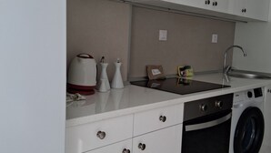 Een kleine keuken met een spoelbak, een wasmachine en een compact fornuis.