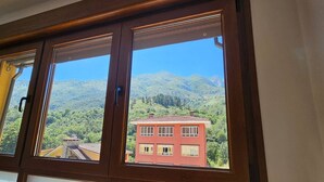Ein Fenster mit Blick auf ein rotes Gebäude und Berge.