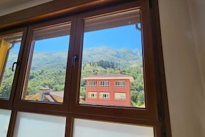 Una ventana con vista a un edificio rojo y montañas.