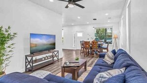 Un salon moderne avec un canapé bleu, un téléviseur et un ventilateur de plafond.