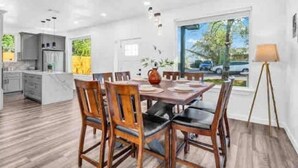 Une cuisine moderne avec des meubles blancs et un coin repas comprenant des chaises et une table en bois.