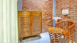 Ein Zimmer mit Backsteinwand, einem Holzschrank, einem Holzbett und einem Waschbecken.