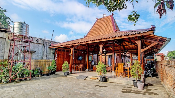 Ein traditionelles Holzhaus mit Ziegeldach, Steinböden und Topfpflanzen.