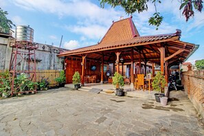 Une maison traditionnelle en bois, avec un toit en tuiles, un sol en pierre et des plantes en pot.