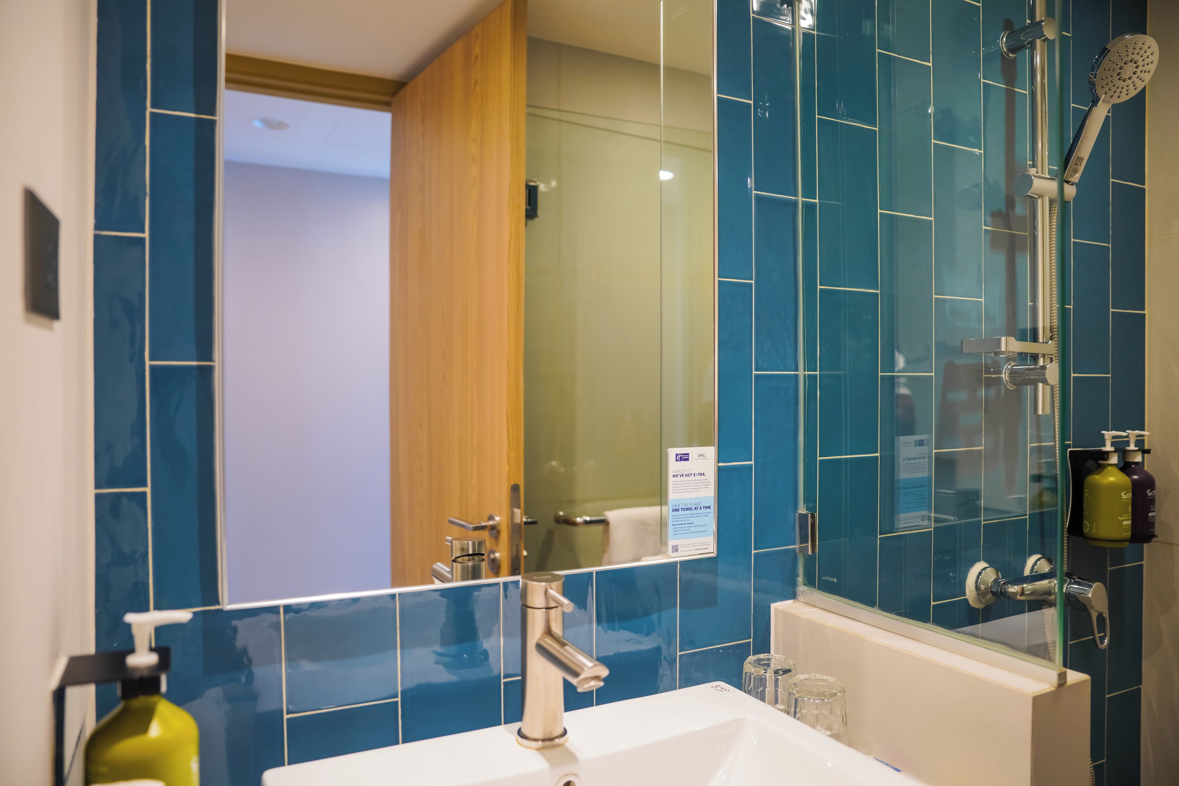 A bathroom with a white sink, a mirror, and a shower with a handheld showerhead.