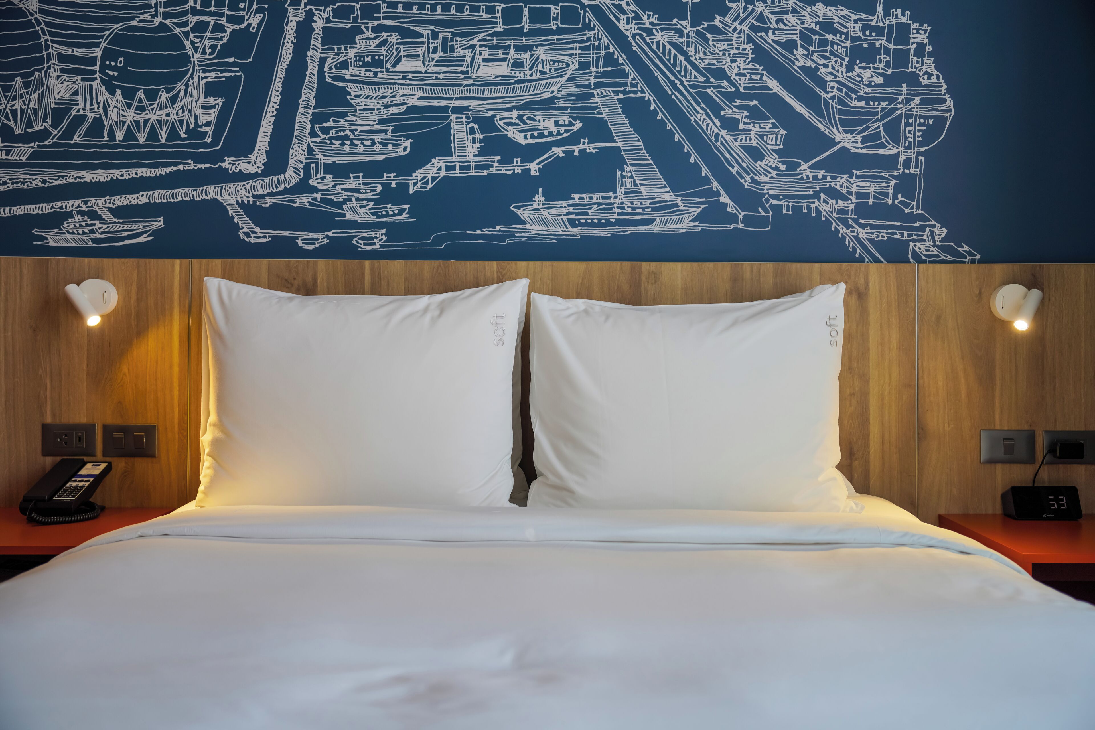 Une chambre d’hôtel avec un lit bien fait, une carte géographique accrochée au mur et une tête de lit en bois.