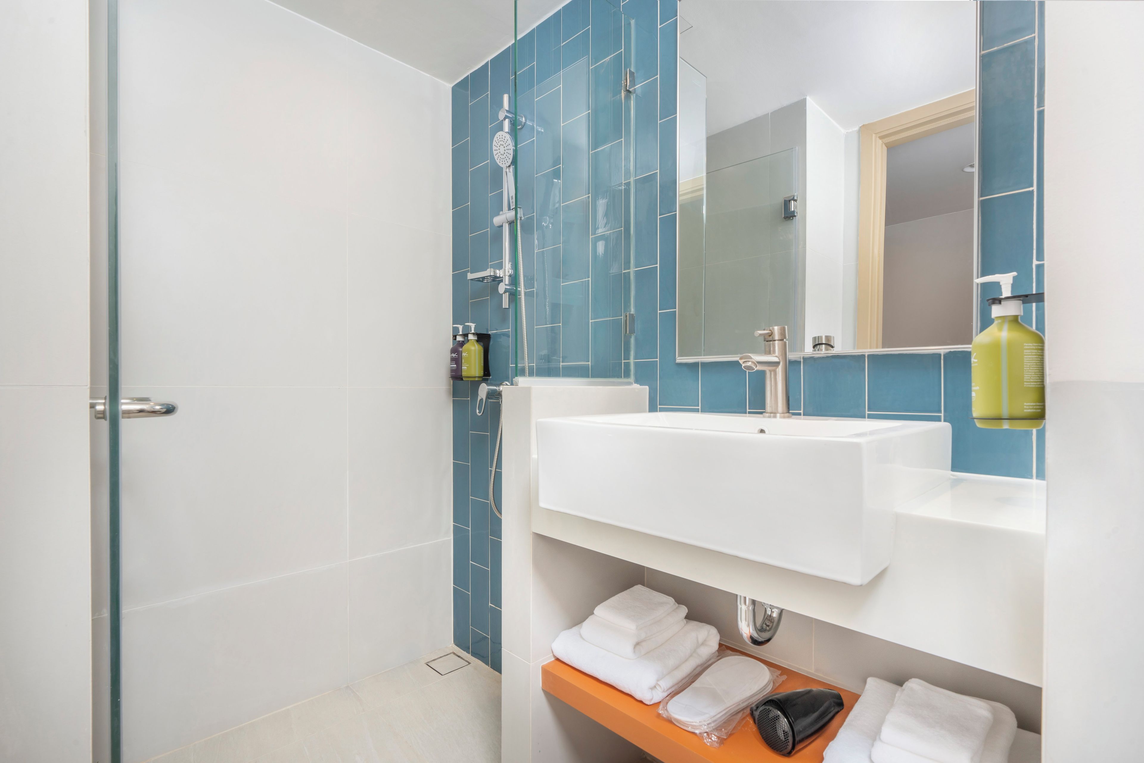 A modern bathroom with a glass shower enclosure, a white sink, and a mirror above it.