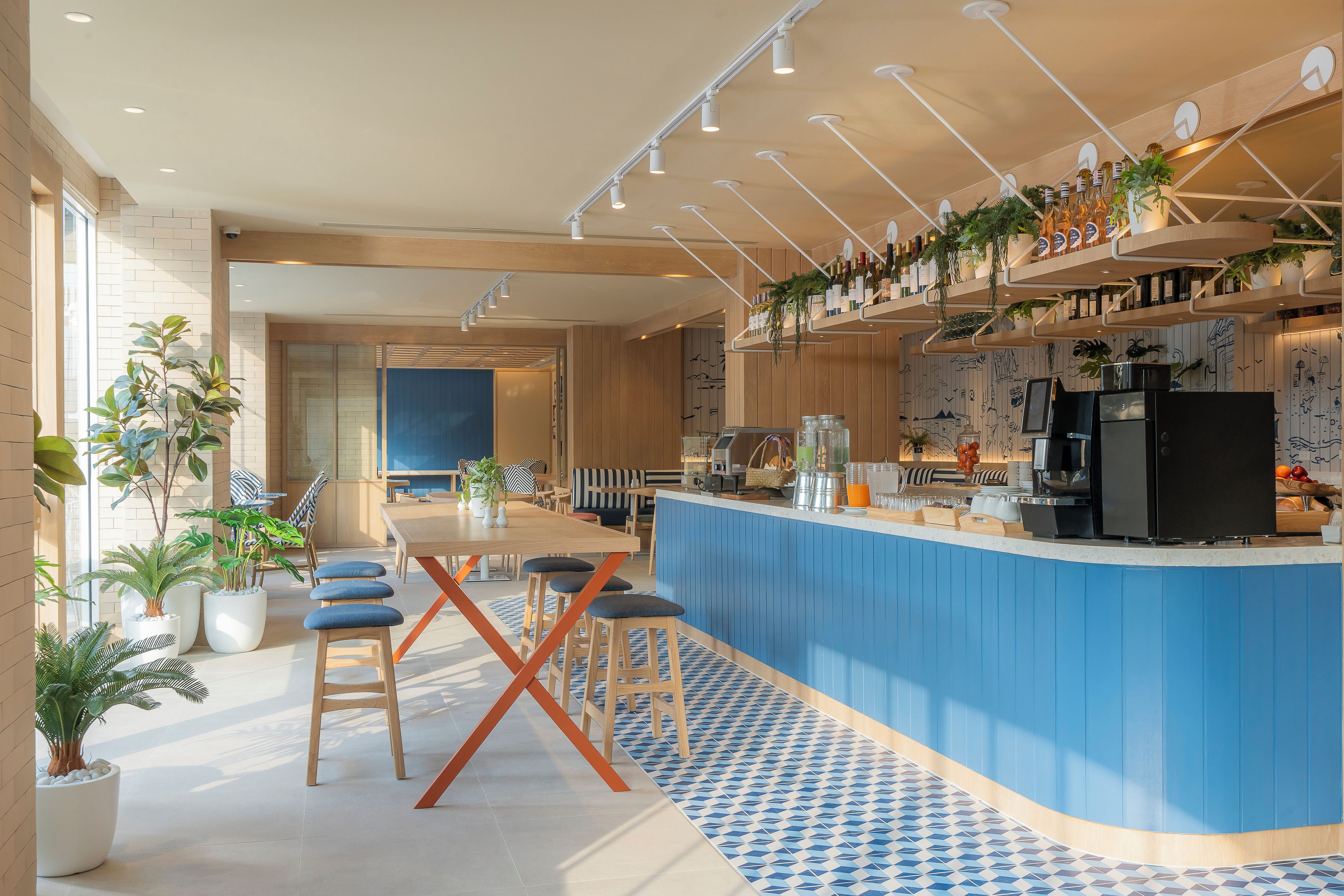 A modern bar area with a blue countertop, bar stools, and a variety of bottles and glasses.