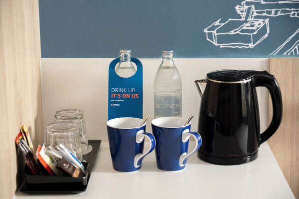 A breakfast setup with two blue mugs, a glass bottle, a black coffee pot, and a tray with condiments. - Holiday Inn Express Rayong by IHG (Rayong)