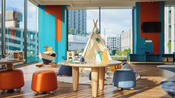 A modern children's play area with a round table, colorful seating, and a teepee play structure.
