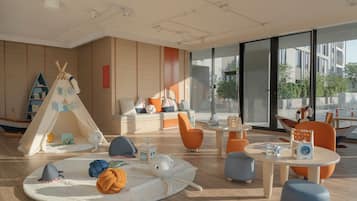 A modern children's play area with a tent, soft seating, and play tables.