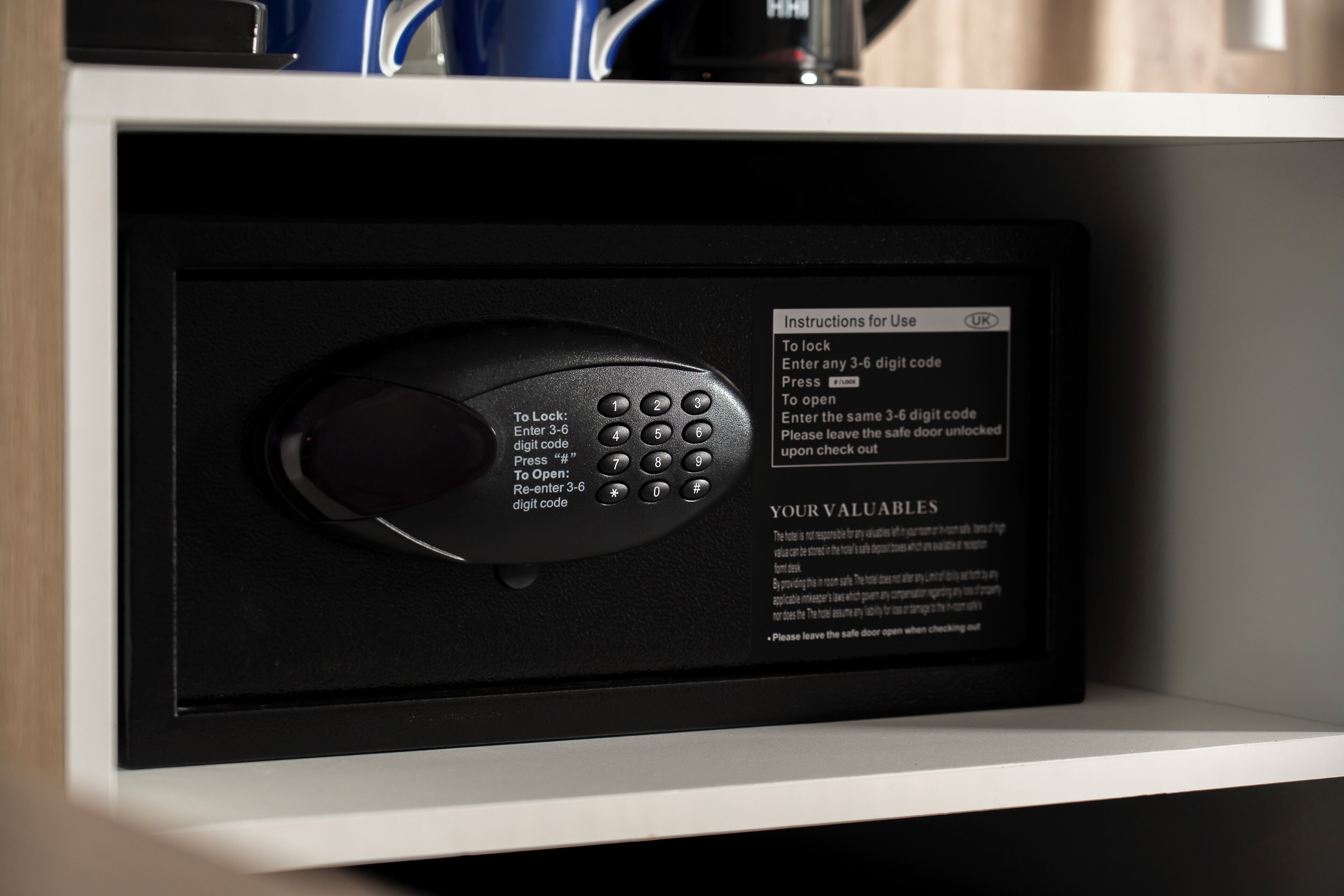 A digital safe with instructions for use, a keypad, and a note about valuables.
