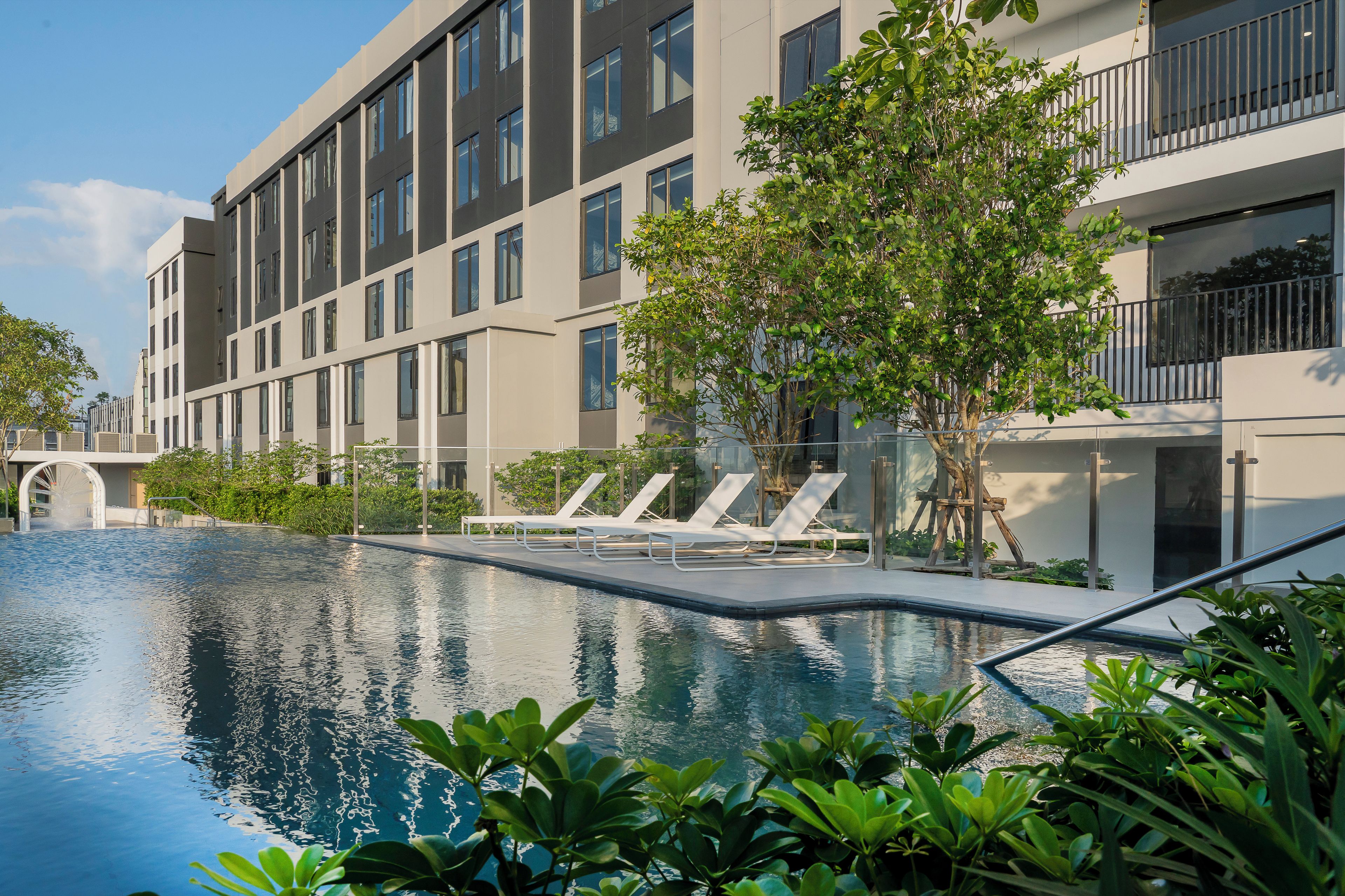Un edificio moderno con piscina y sillones de descanso.