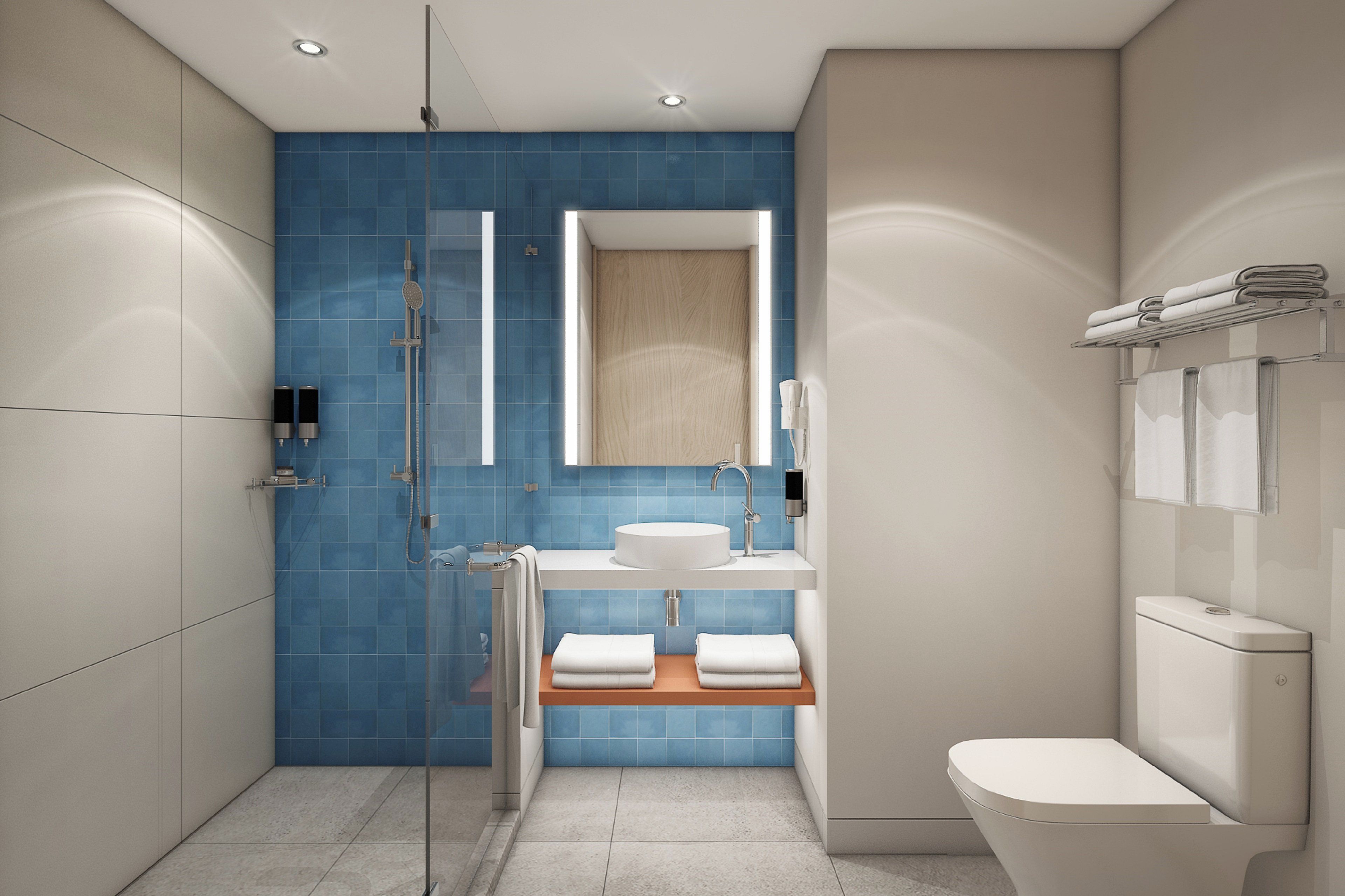 Un baño moderno con cabina de ducha de vidrio, un lavabo blanco y un inodoro.