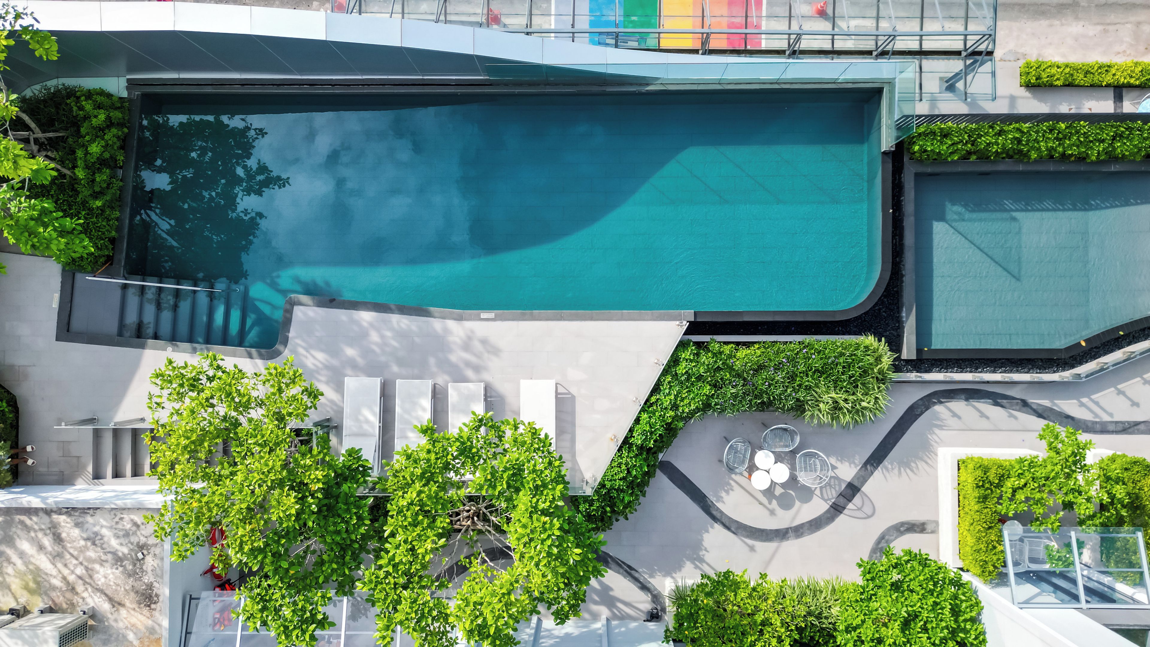 A rooftop pool with a clear view of the sky, surrounded by greenery and modern architecture.