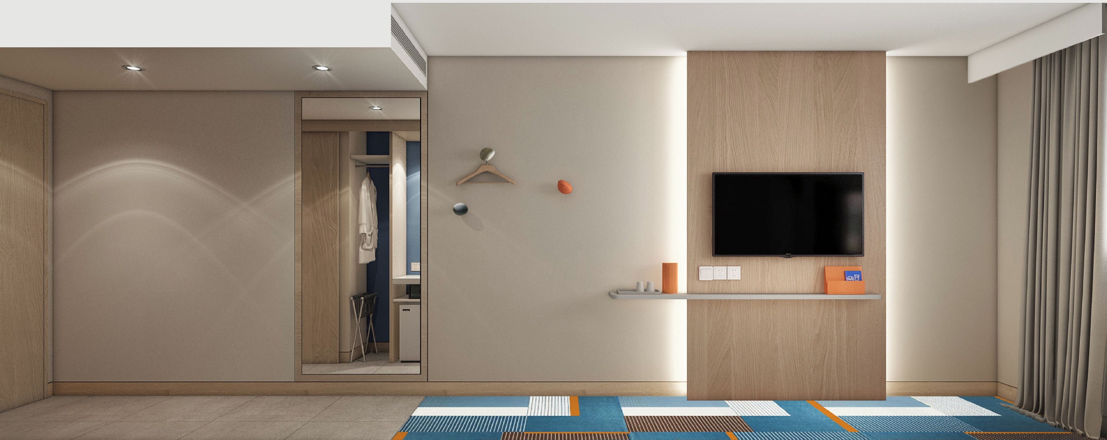 Una habitación de hotel moderna con un televisor de pantalla plana montado en la pared, un estante pequeño con artículos de tocador y una alfombra estampada en el suelo.