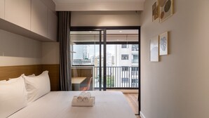 Una habitación de hotel con cama, escritorio y balcón con vistas a la ciudad.