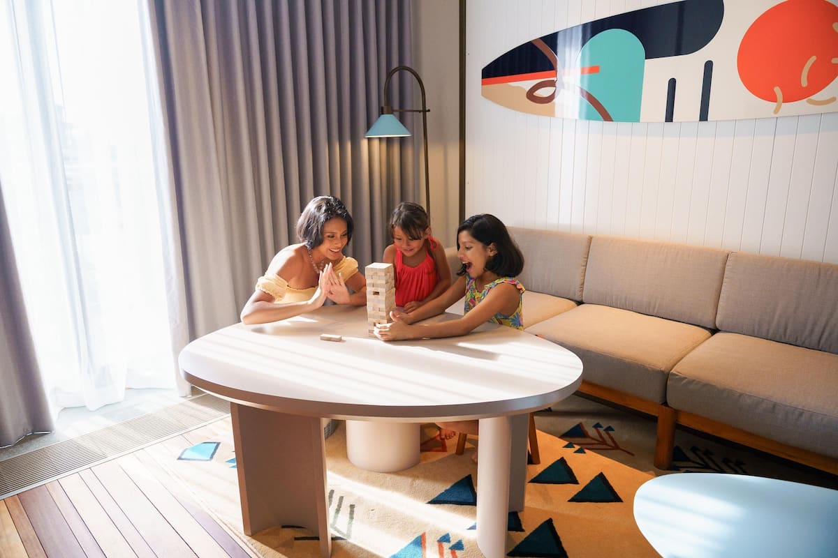 A modern living room with a round table, a sofa, and a colorful abstract wall art.