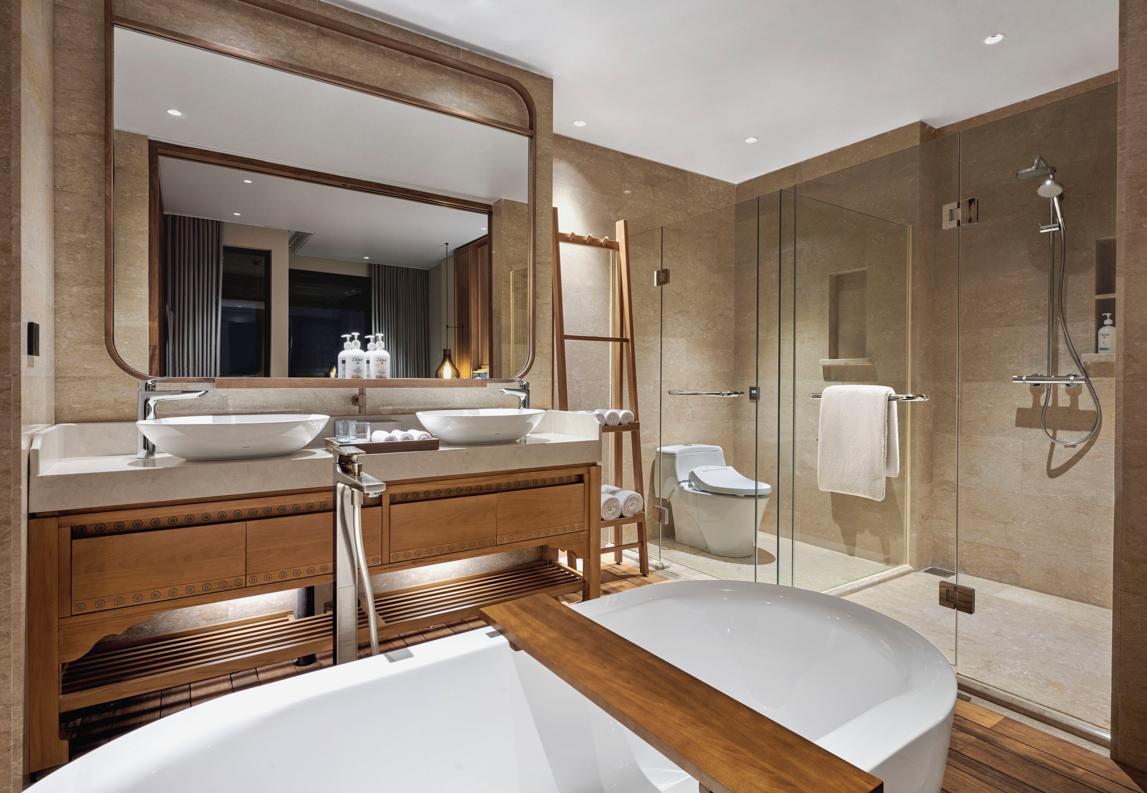 Une salle de bain moderne dotée d’une grande baignoire, de deux vasques, d’une douche à parois de verre et d’un meuble-lavabo en bois.