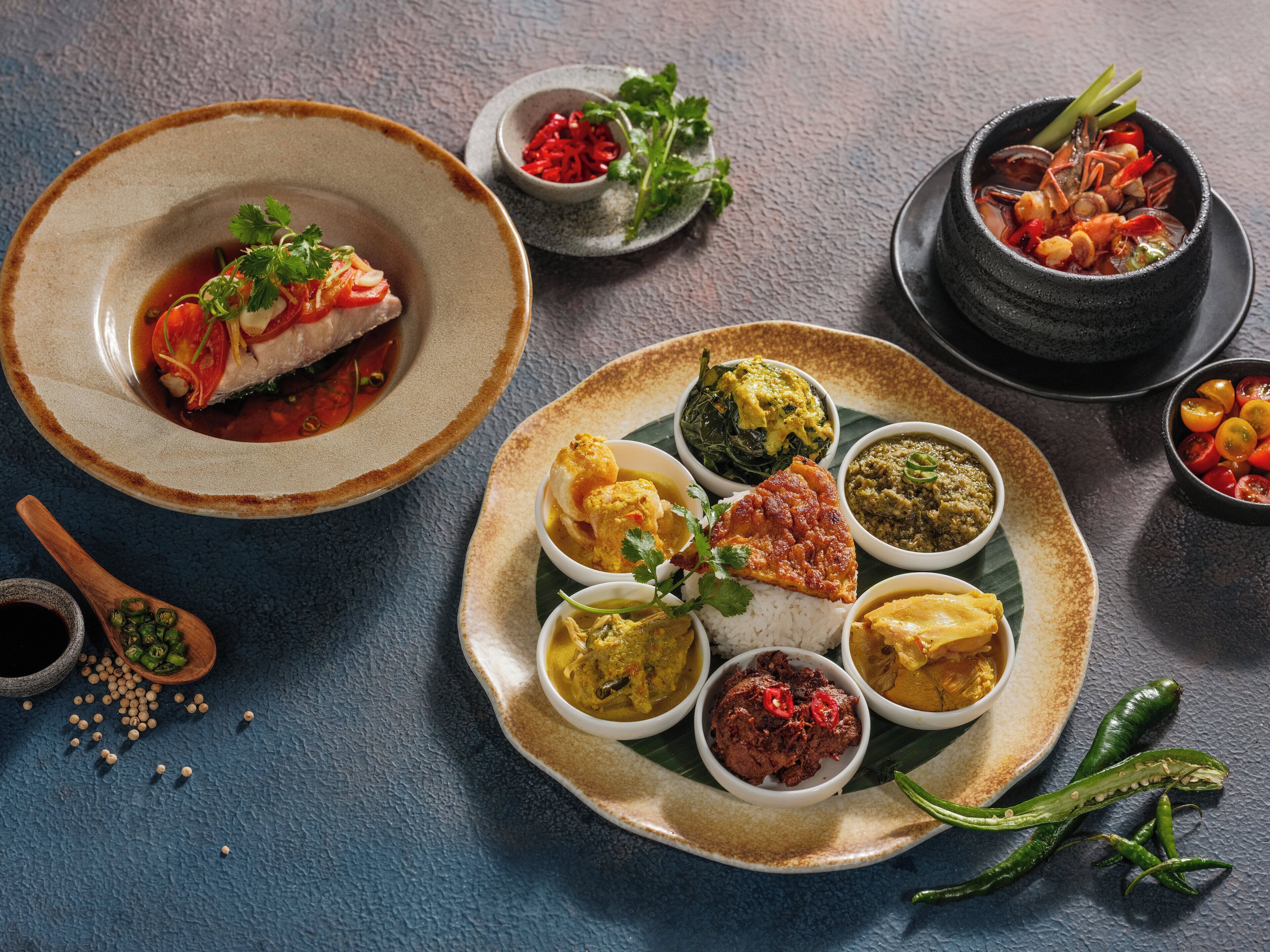 A variety of dishes on a table, including seafood, curries, and rice.
