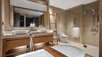 Un baño moderno con un espejo grande, dos lavamanos, una bañera y una ducha con mampara de vidrio.