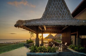 A resort with a thatched-roof structure overlooking the beach, outdoor seating, and a pool area. - Holiday Inn Resort Bali Canggu by IHG (Canggu)