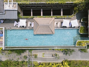 An aerial view of a rooftop swimming pool with lounge chairs and a central decorative structure. - Holiday Inn Resort Bali Canggu by IHG (Canggu)