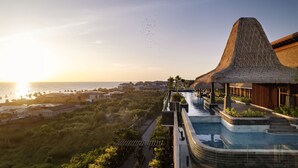 A resort with a pool, a thatched-roof structure, and a view of the ocean. - Holiday Inn Resort Bali Canggu by IHG (Canggu)