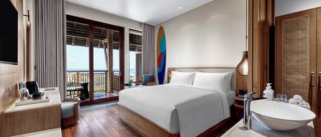 A hotel room with a large bed, a bathroom with a sink and mirror, a coffee station, and a balcony with a view.