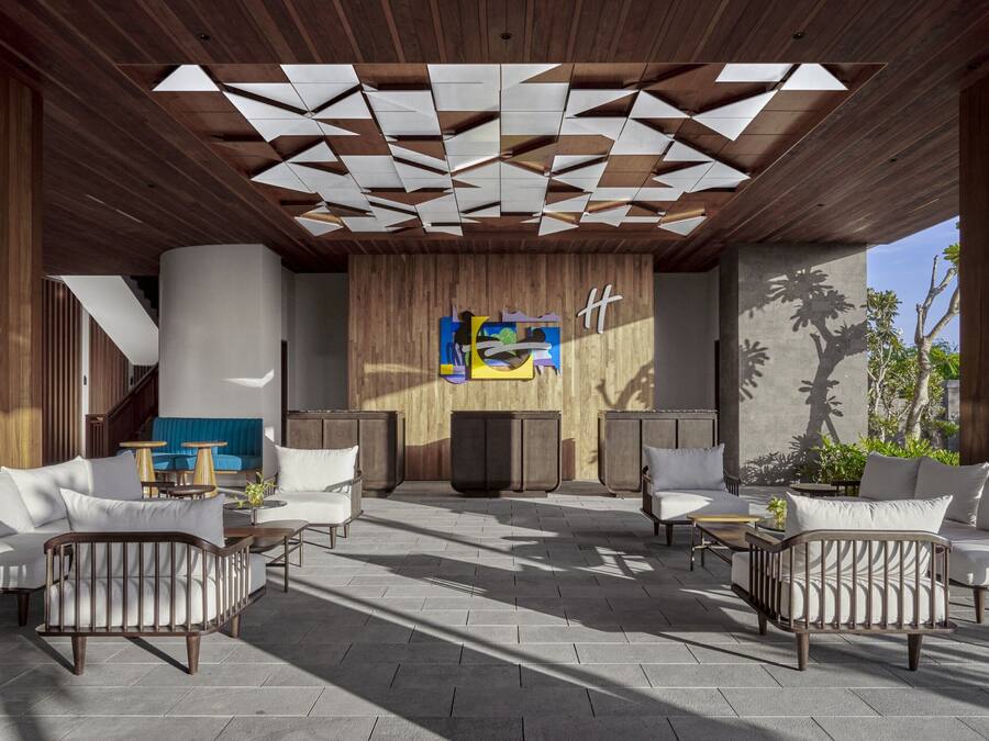 Un área de estar al aire libre con mobiliario de madera y un diseño geométrico en el techo.