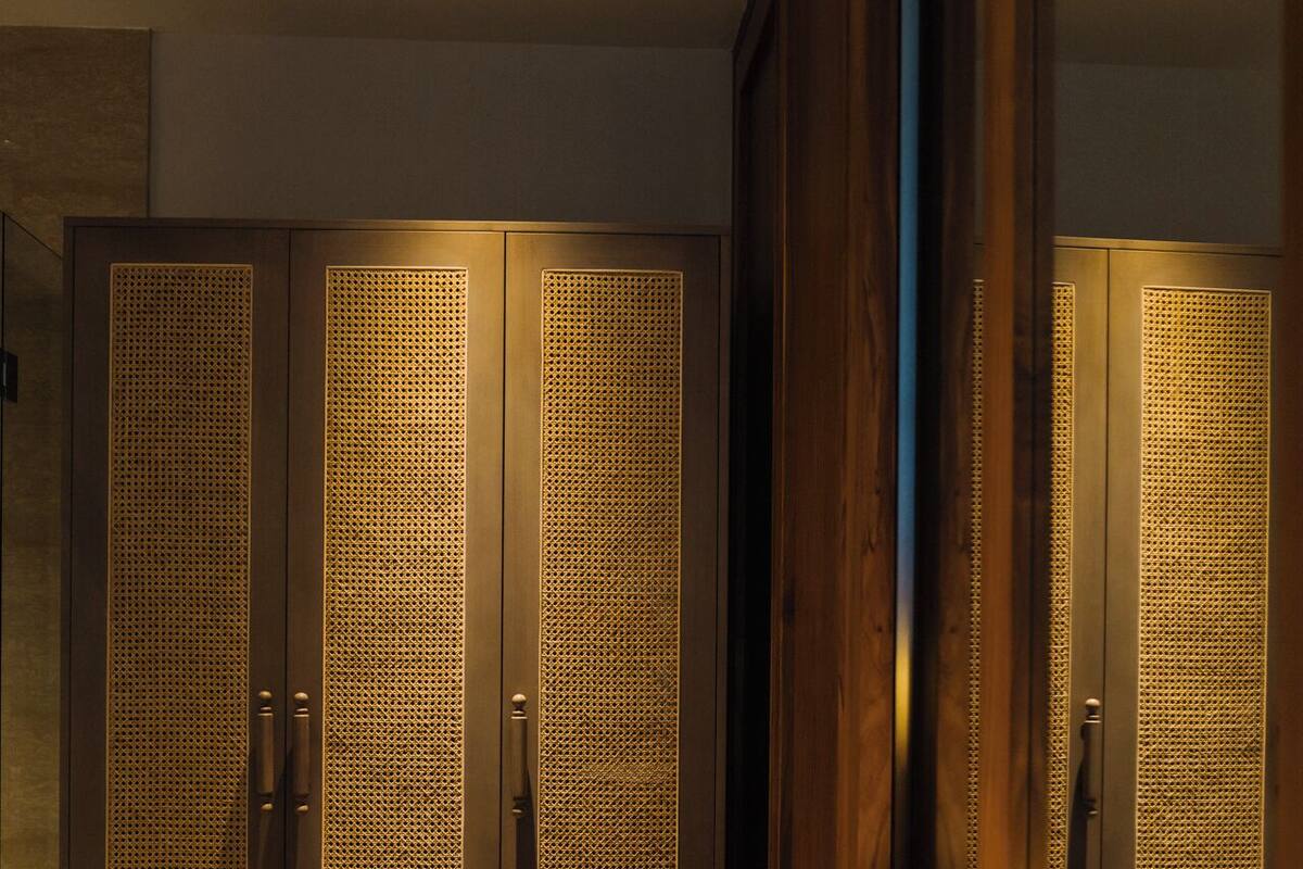 A modern bathroom with a large mirror, a round sink, and wooden cabinets with perforated doors.