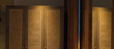 Un baño moderno con un espejo grande, un lavamanos redondo y armarios de madera con puertas perforadas.