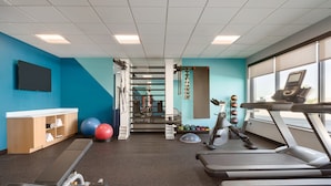 Ein Fitnessraum mit Laufbändern, Gymbällen und einem Gewichtsständer.