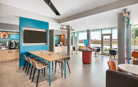 A modern dining area with a wooden table and chairs, a large screen, and a view of the outdoors.