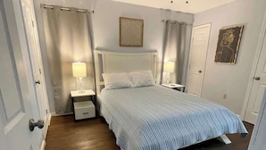 A bedroom with a bed, two bedside tables, a ceiling fan, and a door. - Cozy 2BR 2BA apt close to Siegen & Womans (Baton Rouge)