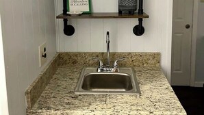 A kitchen with a granite countertop, a stainless steel sink, and three black shelves above it. - Cozy 2BR 2BA apt close to Siegen & Womans (Baton Rouge)