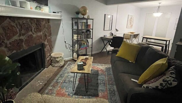 A living room with a fireplace, a sofa, a coffee table, and a bookshelf. - Cozy 2BR 2BA apt close to Siegen & Womans (Baton Rouge)