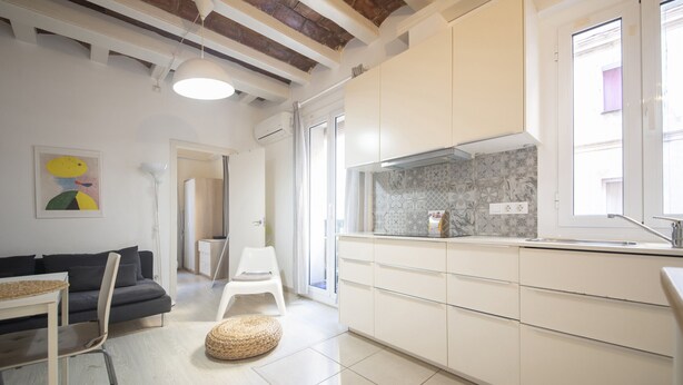 Una cocina moderna con armarios blancos, salpicadero de azulejos y una ventana.