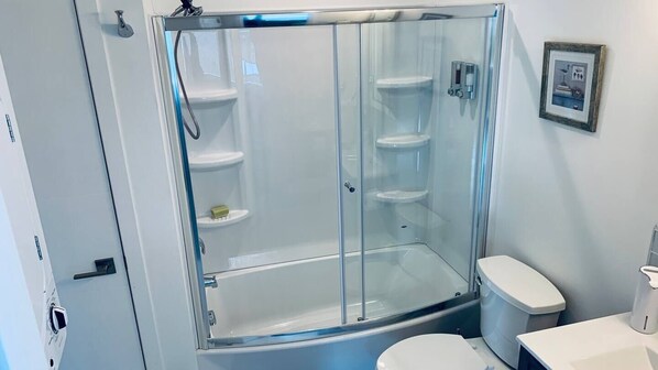 A glass-enclosed shower stall with a toilet and a sink.