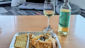 A dining table with a plate of food, a glass of white wine, and a bottle of Palo Alto white blend wine. - Westcoast paradise beside the sea

 (Nanoose Bay)