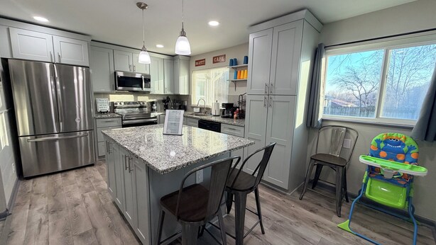 A modern kitchen with granite countertops, stainless steel appliances, and a central island. - ✧KC Speedway Retreat - 10 mins to Everything!✧ (Kansas City)