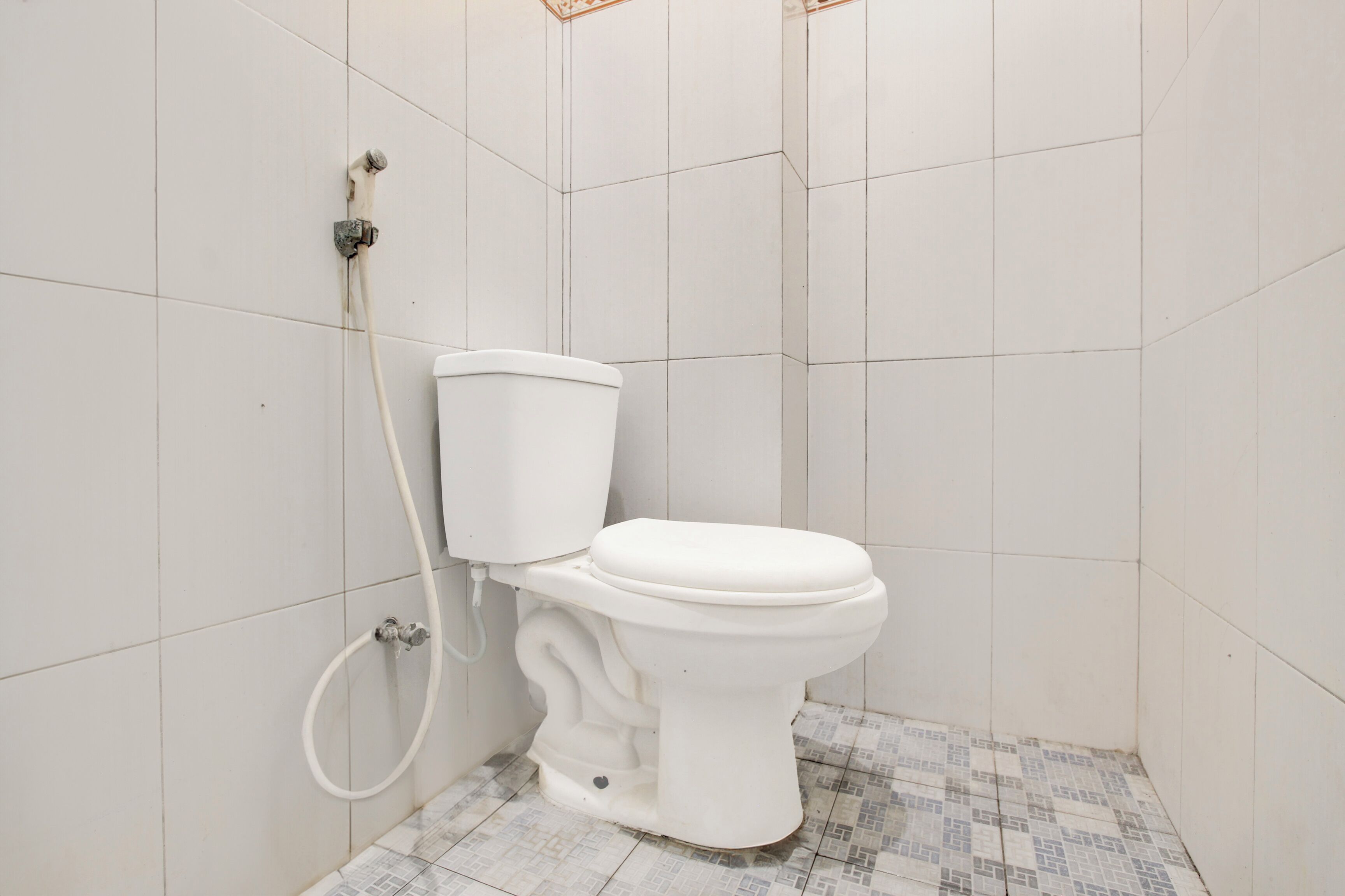 A small bathroom with a toilet, a shower, and a tiled floor.