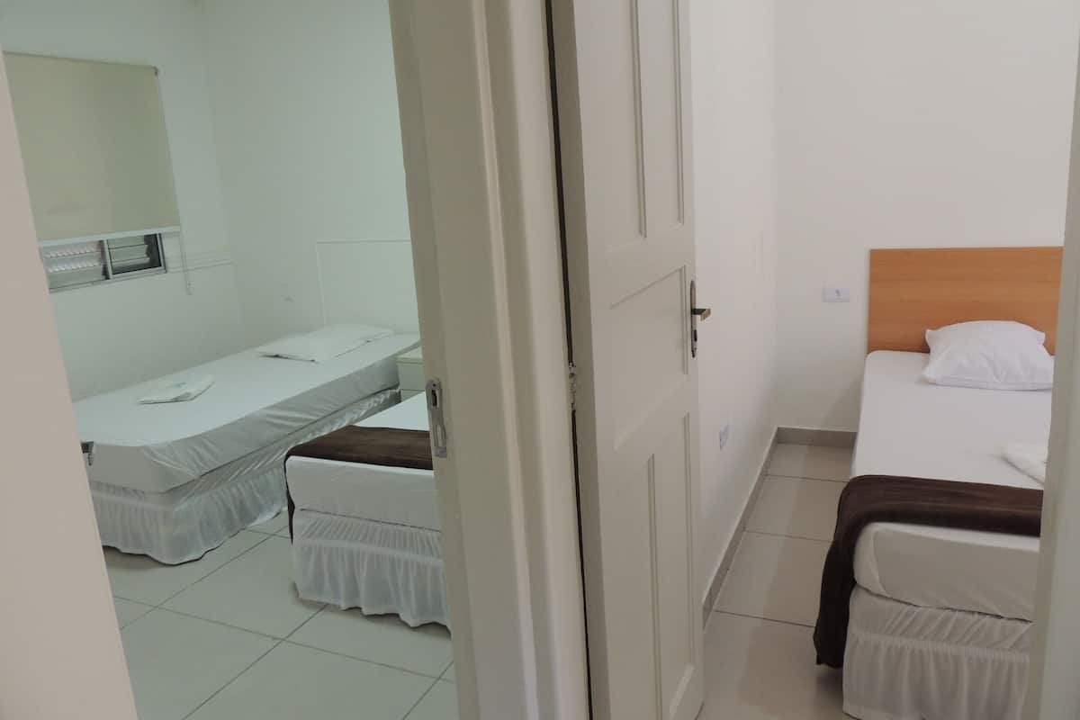 A small, clean room with two beds, a mirror, and a window.