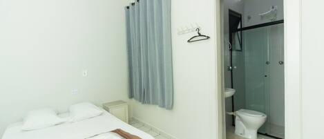 Una habitación de hotel con cama, baño con ducha y retrete.