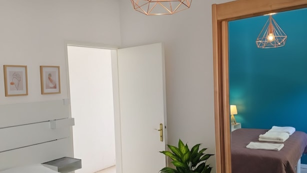 Un dormitorio moderno con una cama grande, una mesita de noche, un espejo y una lámpara colgante.