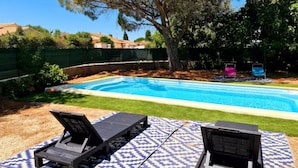 Una piscina con dos sillas de descanso y un colchoneta estampada.