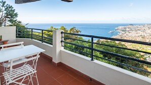 A balcony with a white table and chairs, a drying rack, and potted plants. - Casa da Ângela - By Wehost (Funchal)